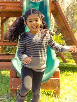 Girl (4-5) laughing coming down slide