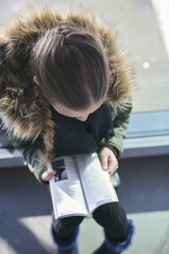 Teen girl (14-15) reading tourist guide book