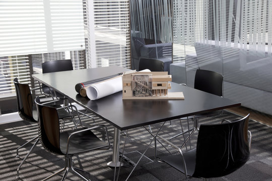Architectural plans and an architectural model on a table in a meeting room