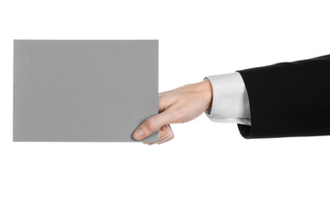 Man in black suit holding a gray blank card in hand isolated