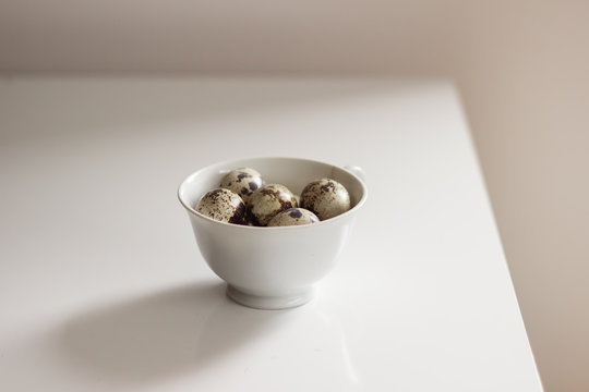 Quail eggs in a bowl on a white table
