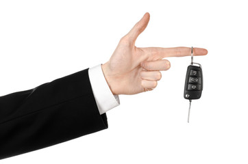 car salesman in a black suit holding a car key isolated