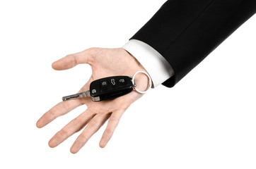 car salesman in a black suit holding a car key isolated