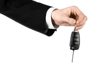 car salesman in a black suit holding a car key isolated