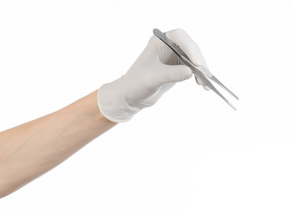 doctor's hand in a white glove holding tweezers isolated studio