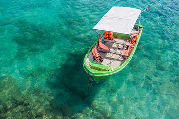 Small green boat floating on the clear water
