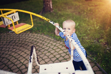 Fototapeta na wymiar Cute little boy in a park on an old carousel.