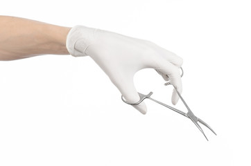 doctor's hand in a white glove holding a surgical clip isolated
