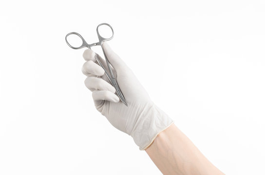 doctor's hand in white glove holding a surgical clamp with swab