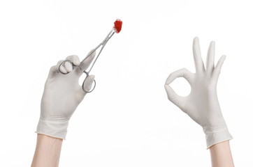 doctor's hand holding a surgical clip with a bloody tampon