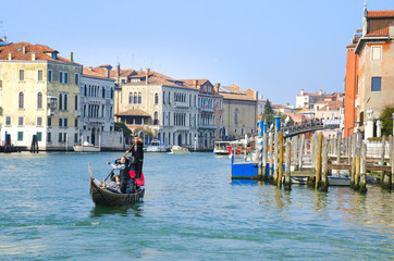 Fototapeta na wymiar Gondola with tourists sailing on a typical Venetian water 