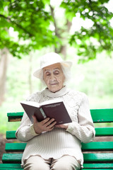 portrait of  happy grandmother on a park bench, read book