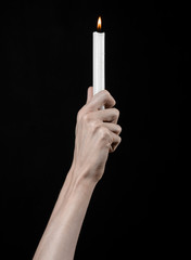 hands holding a candle, a candle is lit, black background