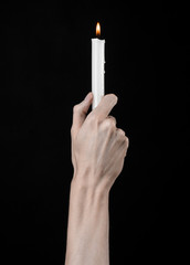 hands holding a candle, a candle is lit, black background