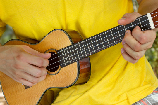 Man's hands playing ukulele