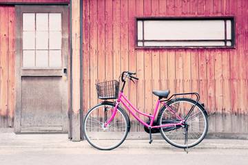 Fototapeta na wymiar Pink bicycle and old wood walls.