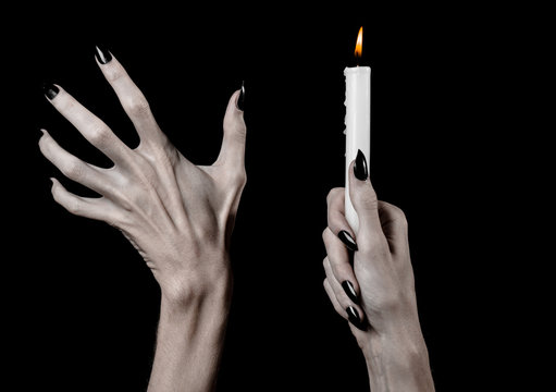 hands holding a candle, a candle is lit, black background