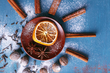 Cinnamon sticks, dried orange, star anise, nutmeg and cloves on color wooden table background