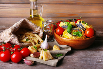 Pasta with cherry tomatoes and other ingredients on wooden table background