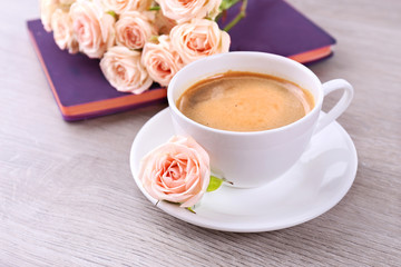 Fresh roses with diary and cup of coffee on wooden background