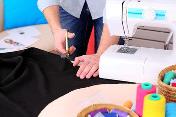 Male dressmaker cut fabric on table close-up