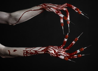 Bloody hand with syringe on the fingers, toes syringes in studio