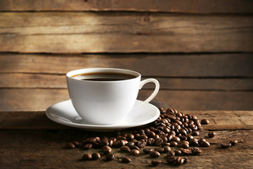 Cup of coffee with grains on wooden background