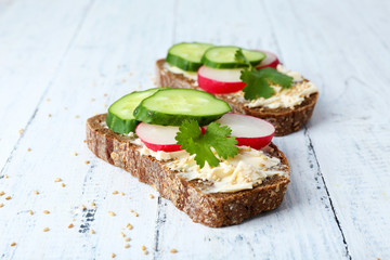 Delicious sandwiches with vegetables and parsley on wooden background