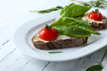 Delicious sandwiches with tomatoes and greens on plate table close up