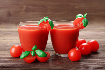 Glasses of tomato juice with vegetables on wooden background