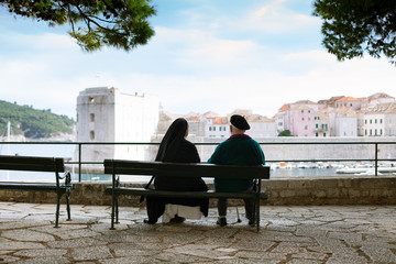 elderly couple sitting on bench watching Dubrovnik panorama