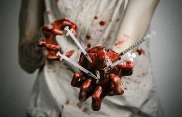 bloody hands addict holding syringe and bloody human heart