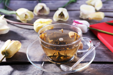 Cup of herbal tea with flowers on wooden table, closeup