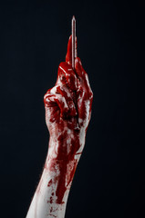 bloody hand holding a large sharp nail isolated  in studio