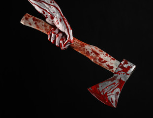 bloody hand holding a bloody butcher's ax isolated in studio