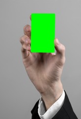 businessman in a black suit and black tie holding a green card