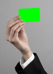 businessman in a black suit and black tie holding a green card