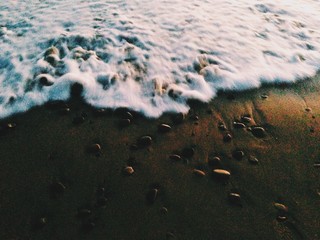 a wave moves over the sand after sunset