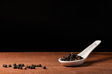 Schwarze Pfeffer Körner auf Porzelan Löffel