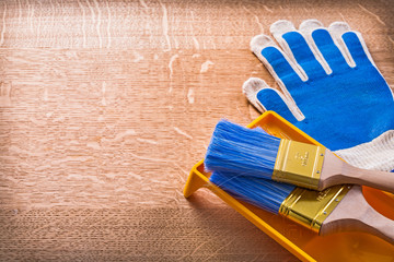 Wooden board with protective gloves paint tray and brushes const