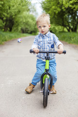 Little boy riding learner bike in park