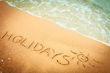 The word holidays written in the sand on a beach