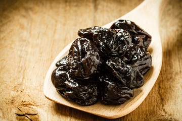 dried plums prunes on wooden spoon