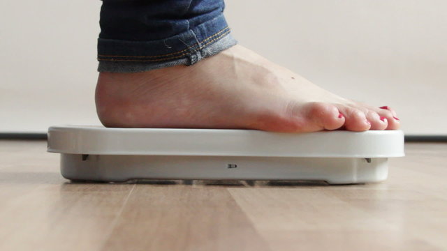 Woman stepping on scales. Full HD 1920X1080P