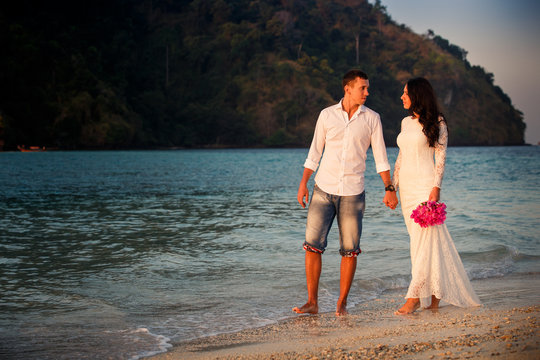 bride and groom walk  at  beach at dawn