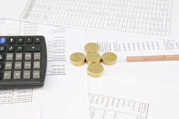 Calculator and pencil between pile of gold coins as plus