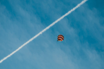 Mongolfiera in volo nel cielo blu con scia bianca