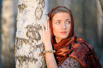 Russian girl in a scarf in a birch forest close up  