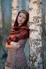 Russian girl in a scarf in a birch forest close up  