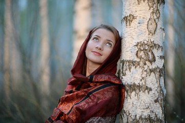 Russian girl in a scarf in a birch forest close up  